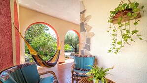 A patio with wicker furniture, a hammock, and a potted plant. - Resonance Experience, Villa Retreat & Sound Healing (Sardegna)