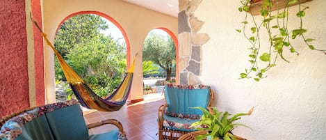 A patio with wicker furniture, a hammock, and a potted plant.