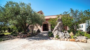 A stone pathway leading to a building with a red roof, surrounded by trees and rocks. - Resonance Experience, Villa Retreat & Sound Healing (Sardegna)