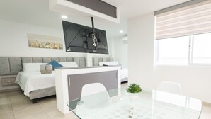 A modern hotel room with a bed, a glass dining table, a small kitchen area, and a large window. - Casa Saza (Cali)