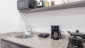 A kitchen with a granite countertop, a microwave, a blender, a coffee maker, a sink, and a stove. - Casa Saza (Cali)