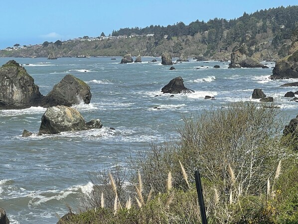 A coastal landscape with rocky outcrops and waves crashing against them.