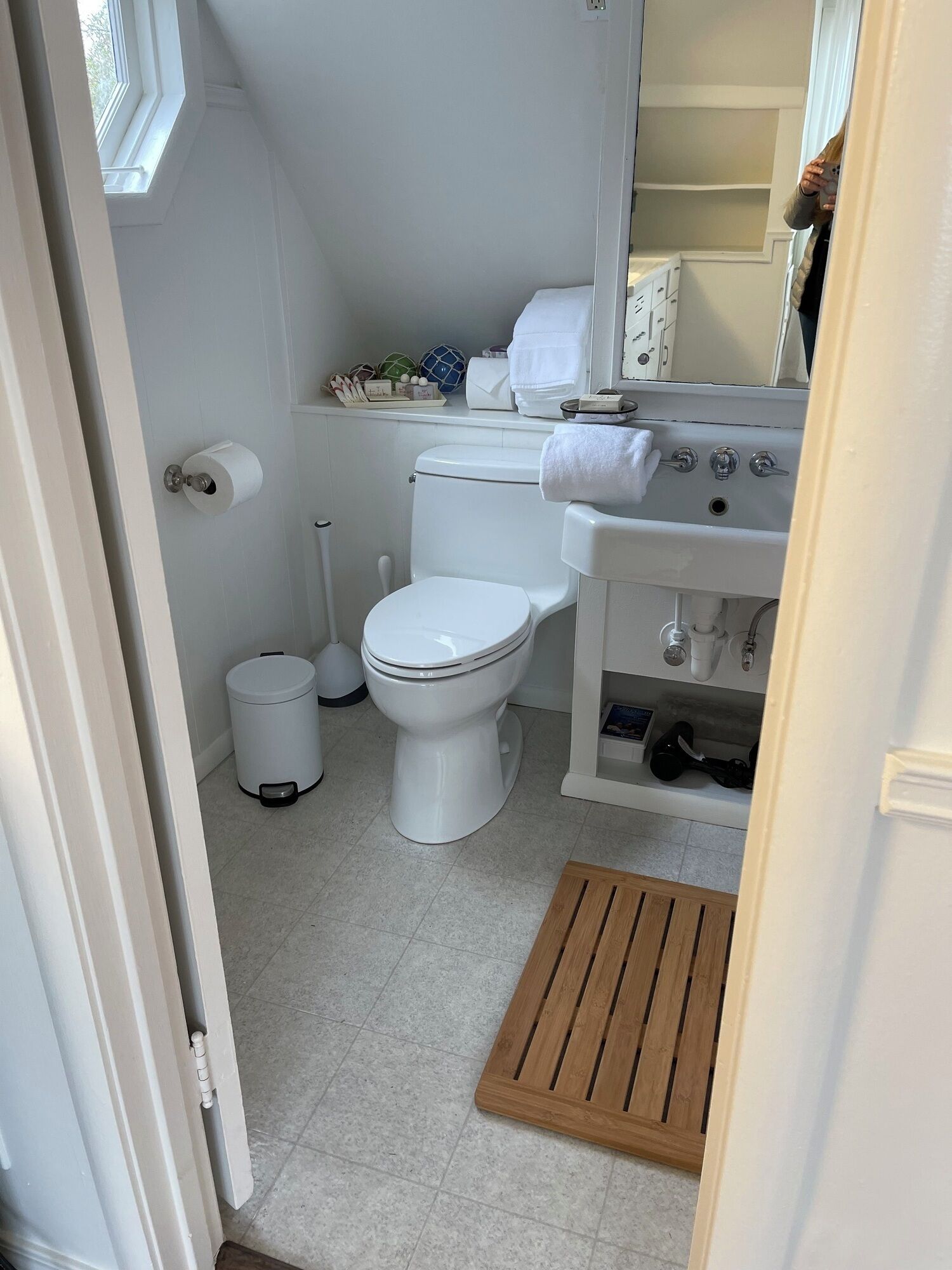 Een kleine, schone badkamer met toilet, wastafel en een raam.