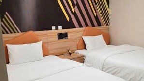 Een hotelkamer met twee bedden, elk met witte beddengoed en oranje hoofdeinden. Er is een houten hoofdeinde met een klein bord boven de bedden.