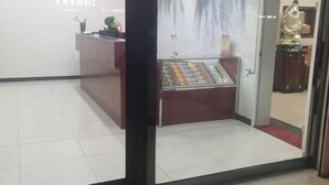 Een receptiegedeelte met een receptiebalie, een glazen vitrine met objecten, en een standbeeld.