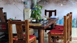 Een houten eettafel met stoelen, een potplant en diverse spullen op de tafel.
