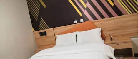 Uma cama com roupa de cama branca, cabeceira de madeira e parede com padrão geométrico.