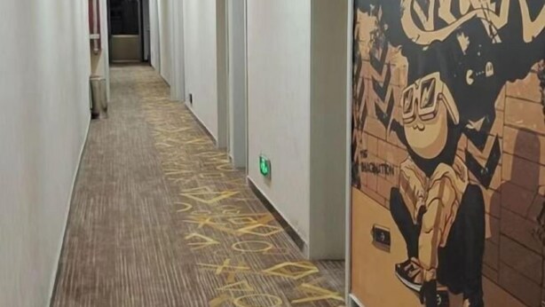 Een hotelgang met een kamerbreed tapijt en een muurschildering.
