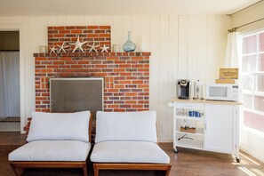 A room with a brick fireplace, two cushioned chairs, a coffee maker, a microwave, and a window with curtains. - Large, Comfortable Room with views of both the Ocean and The Bay! (Trinidad)