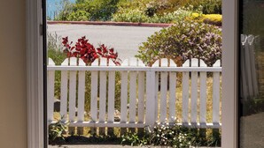 A door opening to a balcony with a view of the sea and a white picket fence. - Large, Comfortable Room with views of both the Ocean and The Bay! (Trinidad)