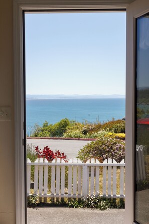 A door opening to a balcony with a view of the sea and a white picket fence. - Large, Comfortable Room with views of both the Ocean and The Bay! (Trinidad)