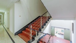 Un escalier moderne avec une rampe en verre, menant à l’étage supérieur.