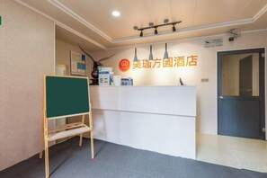A reception area with a reception desk, a greenboard, and a door. - Wujiang Fangyuan Hotel (Suzhou)