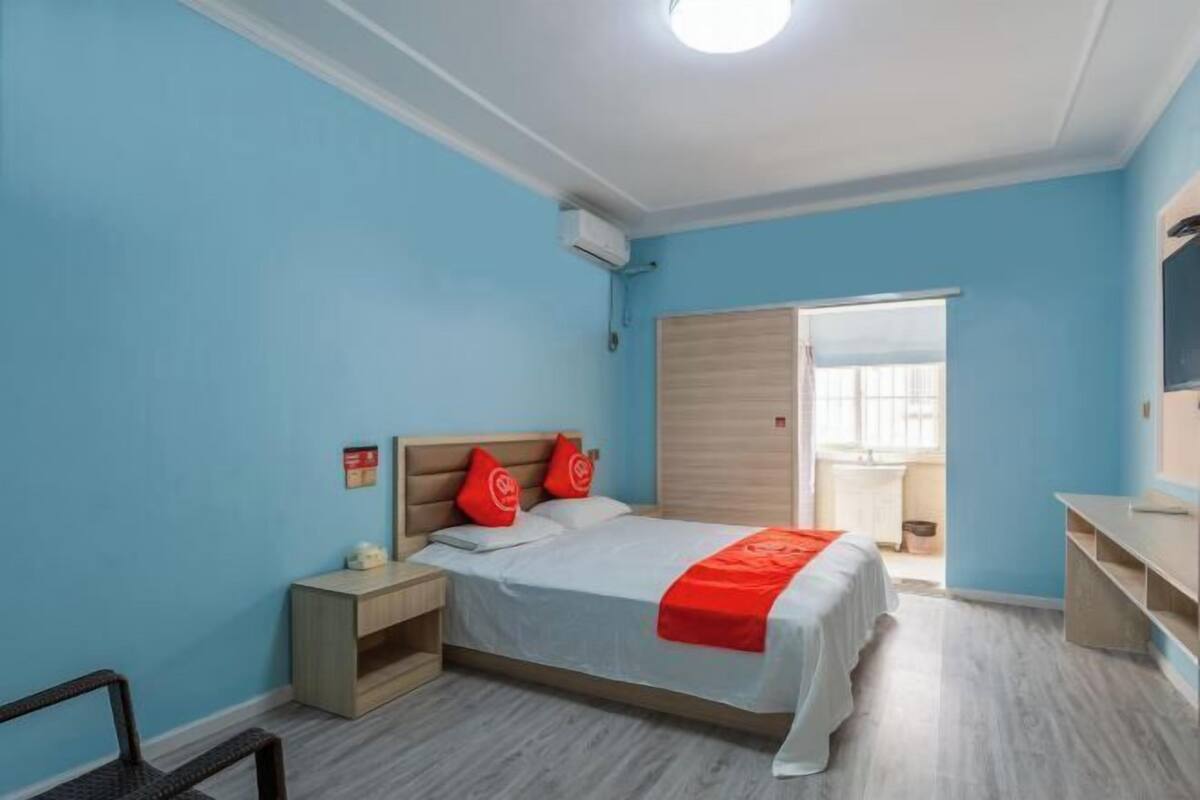 Un dormitorio con cama, mesitas de noche, un escritorio y una ventana.