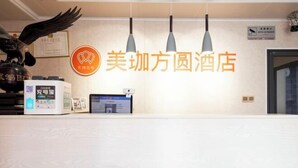 Un comptoir d’accueil avec une enseigne indiquant « 美桐方圆酒店 » et une sculpture d’oiseau décorative.