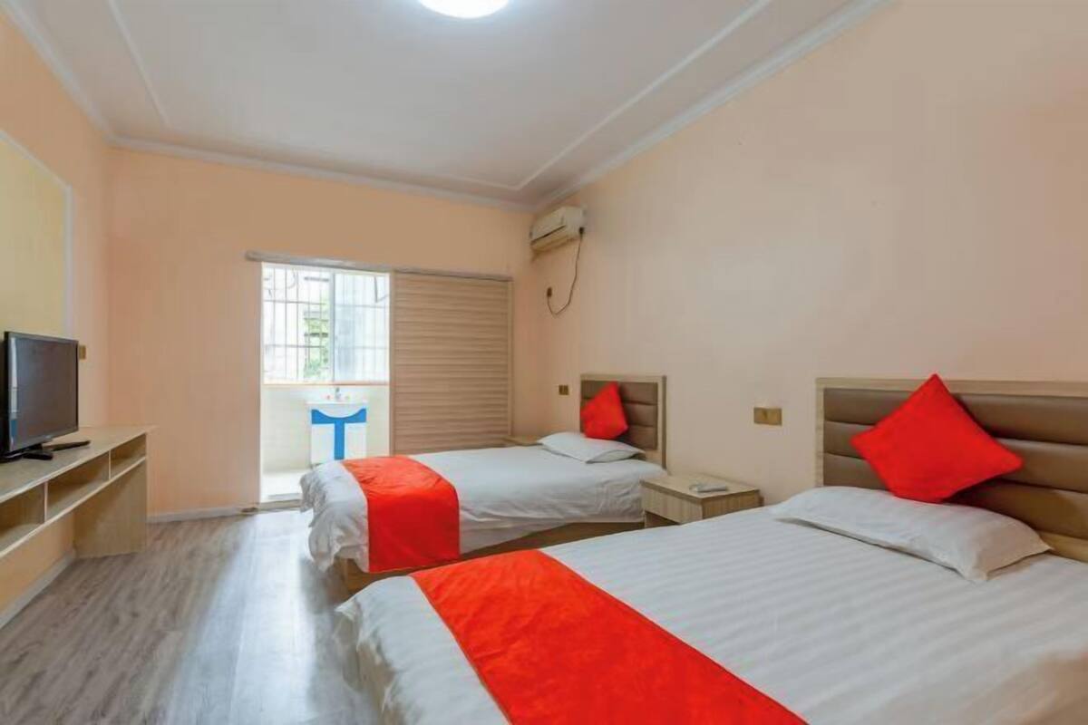 Habitación de hotel con dos camas, televisión y ventana con persianas.