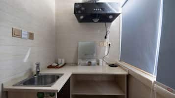 A bathroom with a sink, mirror, towel dispenser, and a shower area with a control panel.