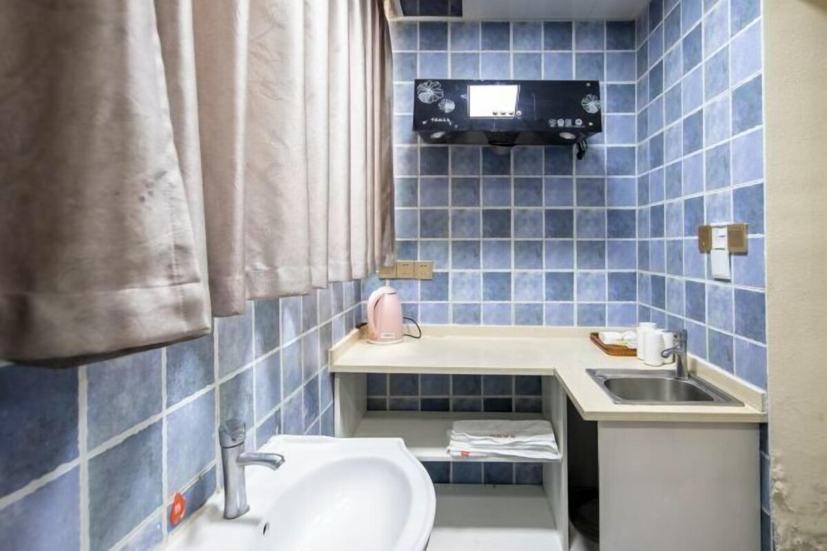 Ein kleines Badezimmer mit blauen Fliesen, einem weißen Waschbecken, einer kleinen Ablagefläche und einem Handtuchhalter.