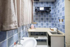 Ein kleines Badezimmer mit blauen Fliesen, einem weißen Waschbecken, einer kleinen Ablagefläche und einem Handtuchhalter.