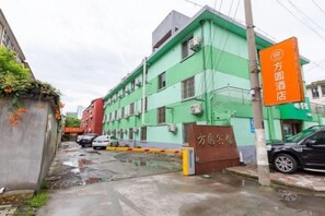 Un edificio con fachada verde, letrero de hotel y entrada protegida por una reja.