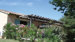 A building with a tiled roof, a wooden pergola, and a garden with flowering plants. - Mazet Provençal air-conditioned swimming pool parking 5 pers (Gaujac)