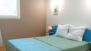 A bedroom with a bed, a nightstand, a lamp, and a window. - Mazet Provençal air-conditioned swimming pool parking 5 pers (Gaujac)