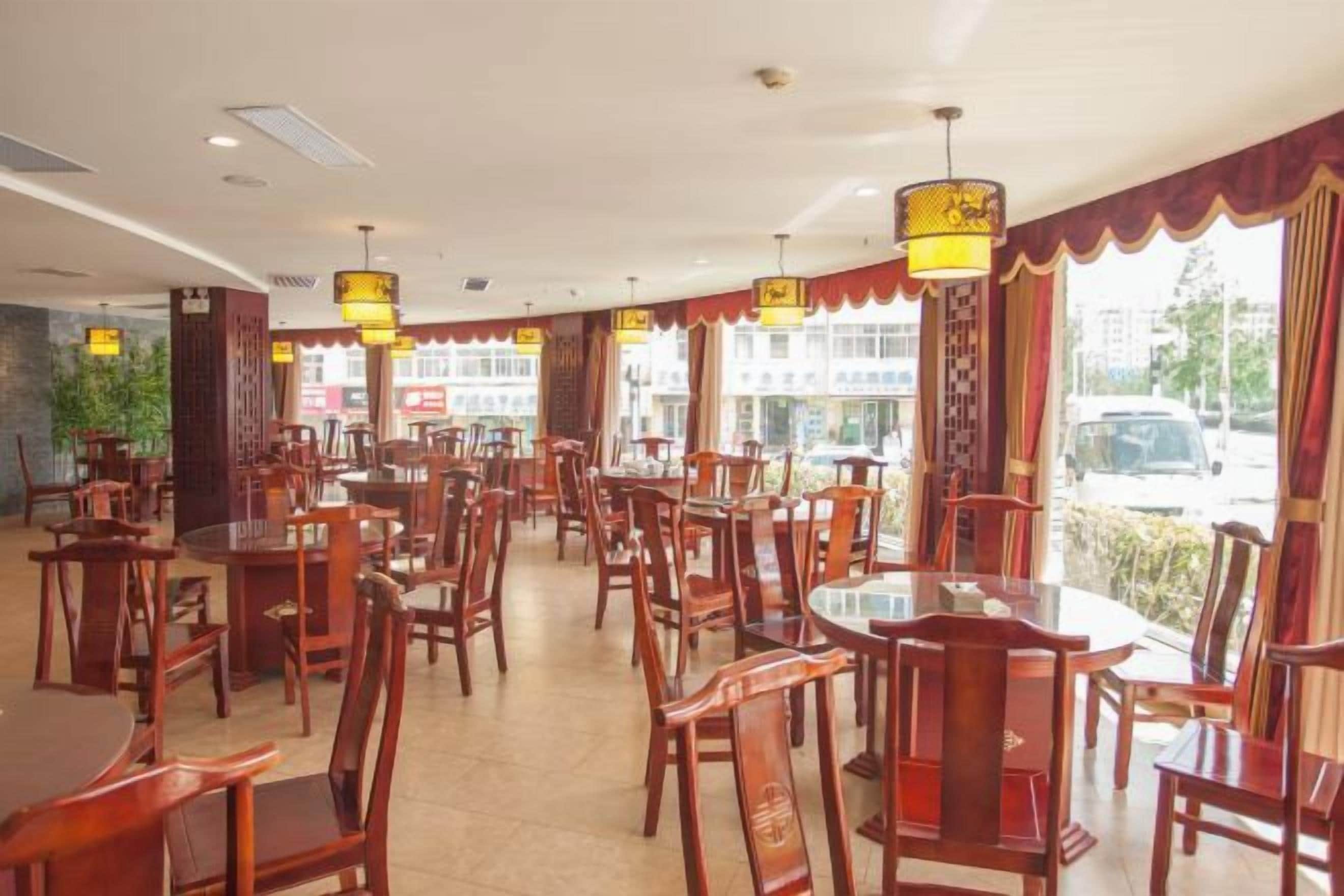 Un ristorante con diversi tavoli e sedie, ampie finestre e lampadari.