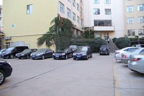 A parking lot with several cars, a staircase leading to a building, and a yellow building with multiple windows. - Keriya Hotel (Qingdao Golden Beach Branch) (Qingdao)