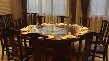 A round dining table set for six with chairs, a glass centerpiece, and a brick wall in the background.