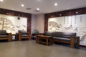 A room with a sofa, chairs, and a table. There are wall decorations with trees and birds. - Keriya Hotel (Qingdao Golden Beach Branch) (Qingdao)