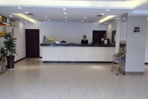 A hotel reception area with a reception desk, a potted plant, and a sign indicating a smoking area. - Keriya Hotel (Qingdao Golden Beach Branch) (Qingdao)