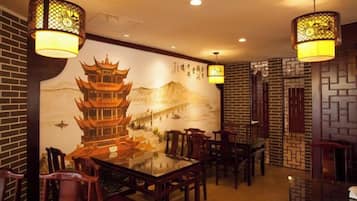 L’intérieur d’un restaurant chinois traditionnel, avec une fresque murale, des meubles en bois et des lanternes suspendues.