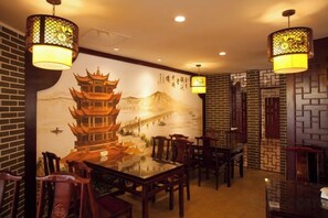 L’intérieur d’un restaurant chinois traditionnel, avec une fresque murale, des meubles en bois et des lanternes suspendues.