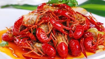 A dish of cooked crayfish with sauce and garnish.