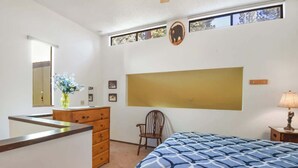 A bedroom with a bed, dresser, chair, and a large mirror.