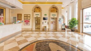 A hotel lobby with a checkered floor, a reception desk, a television, and a large plant. - Langshan Hotel (Songshan Lake Vanke Songfo Subway Station Store) (Dongguan)