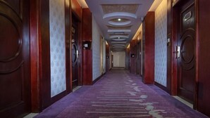 A long hallway with doors on both sides, carpeted floor, and patterned ceiling. - Langshan Hotel (Songshan Lake Vanke Songfo Subway Station Store) (Dongguan)