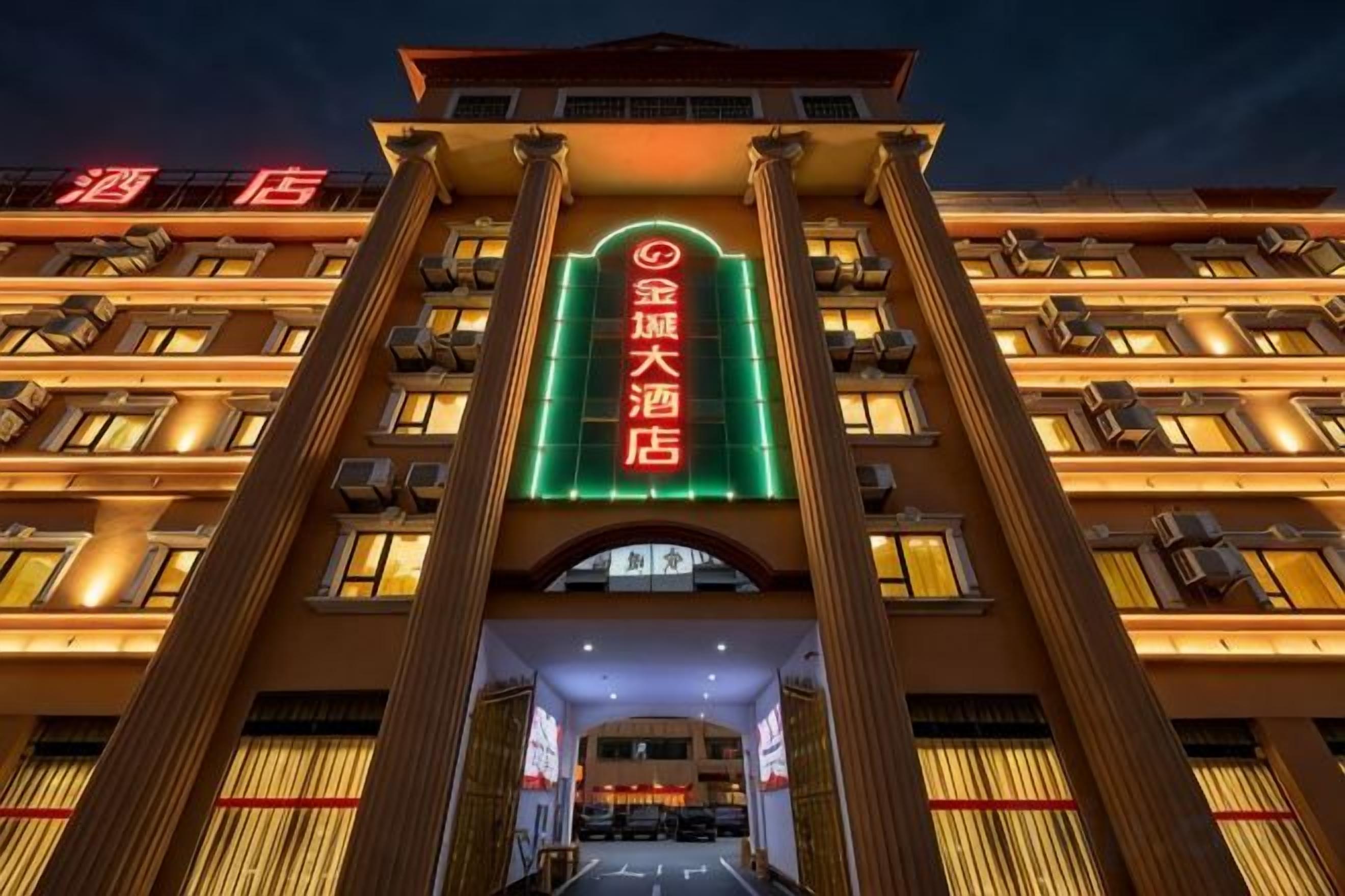 A hotel entrance with a prominent archway and illuminated signage.