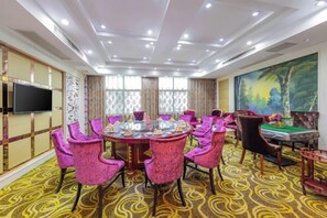 A conference room with a round table, pink chairs, a pool table, and a large painting on the wall. - Jincheng Hotel (Zigui)