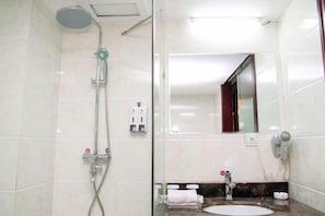 Un baño con ducha, lavamanos, espejo y toallero.