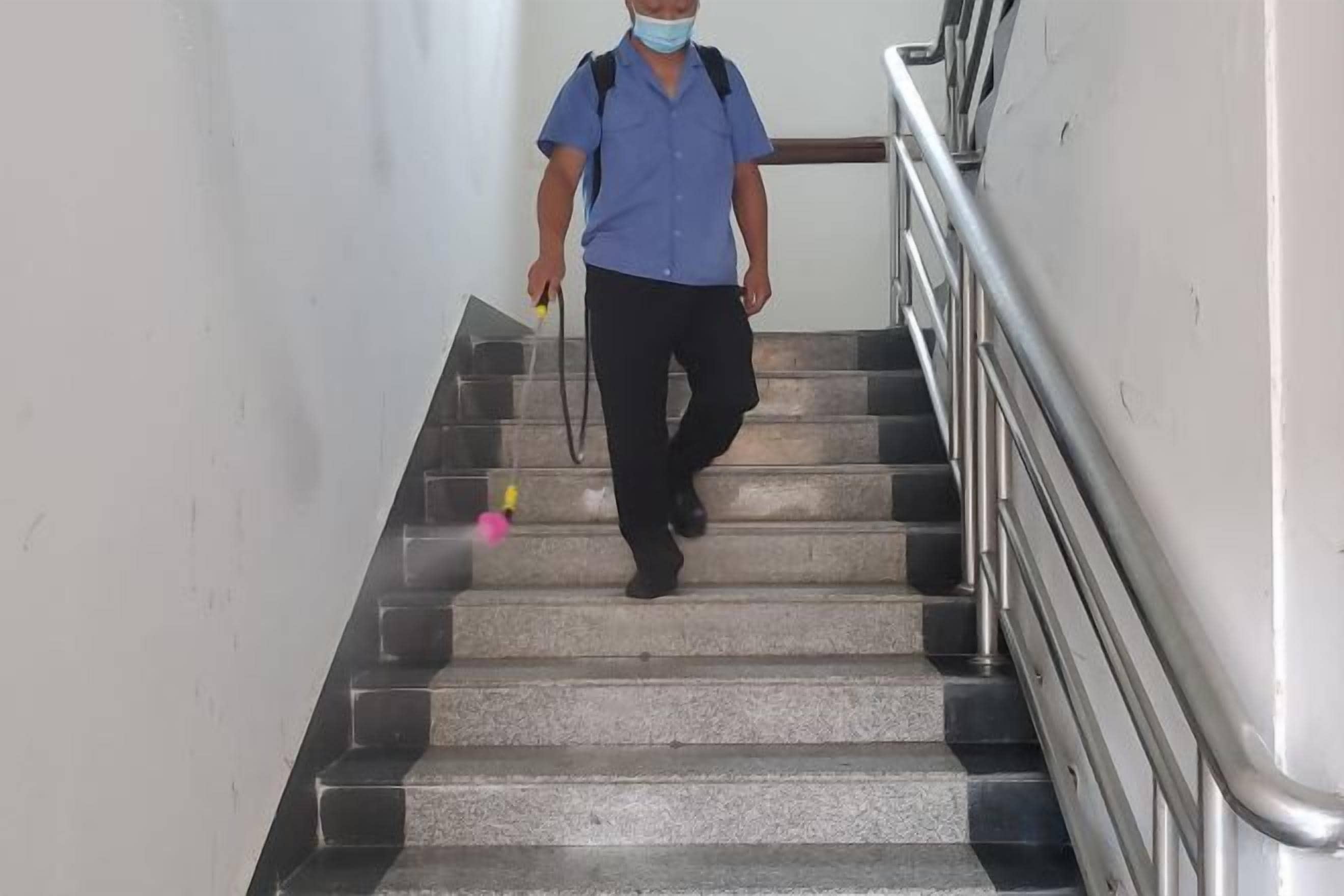 A person descending a staircase with a handrail on one side.