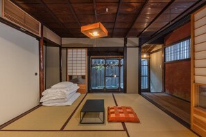 Um quarto japonês tradicional com tatames, teto de madeira baixo e portas corrediças.