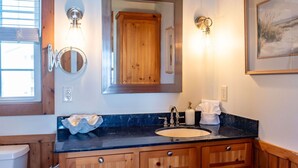 A bathroom with a wooden vanity, a sink, a mirror, and a framed picture on the wall. - Unbeatable Views & Coastal Charm (Harkers Island)
