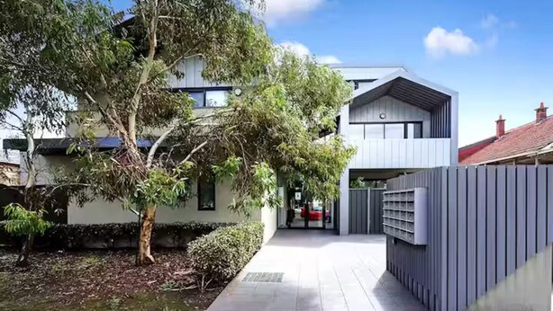A modern two-story house with a covered driveway and a fenced garden area.