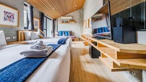 A modern hotel room with a bed, a TV, a wooden desk, and a ceiling with wooden slats. - Harajuku Inn (Pingtung)