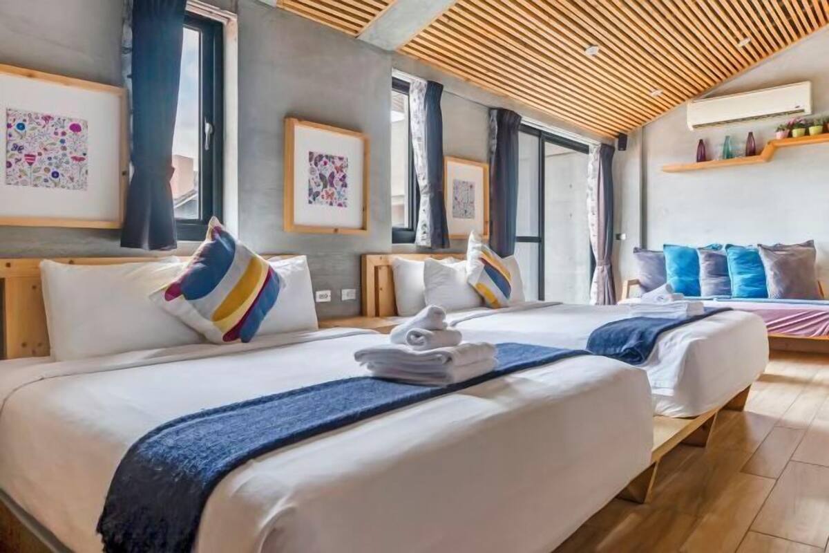 Camera d'albergo con due letti, soffitto in legno, opere d'arte alle pareti e una finestra.