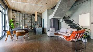 A modern interior with a dining area, kitchen, staircase, and seating.