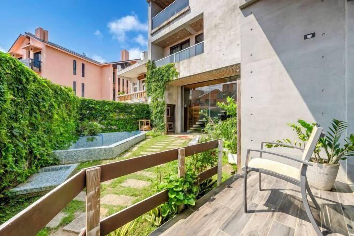 Un edificio moderno con un balcone, una recinzione in legno e una sedia.