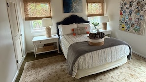 A bedroom with a bed, a nightstand, a ceiling fan, and a wall with a bulletin board. - The Sweet Spot SB (Santa Barbara)