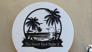 A circular sign with a beach scene, palm trees, and the text "The Sweet Spot Suite A". - The Sweet Spot SB (Santa Barbara)
